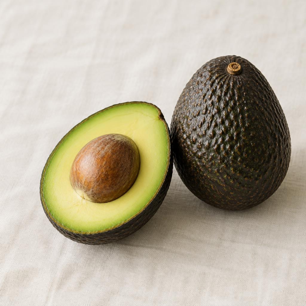 Aguacate Hass abierto por la mitad junto a uno entero